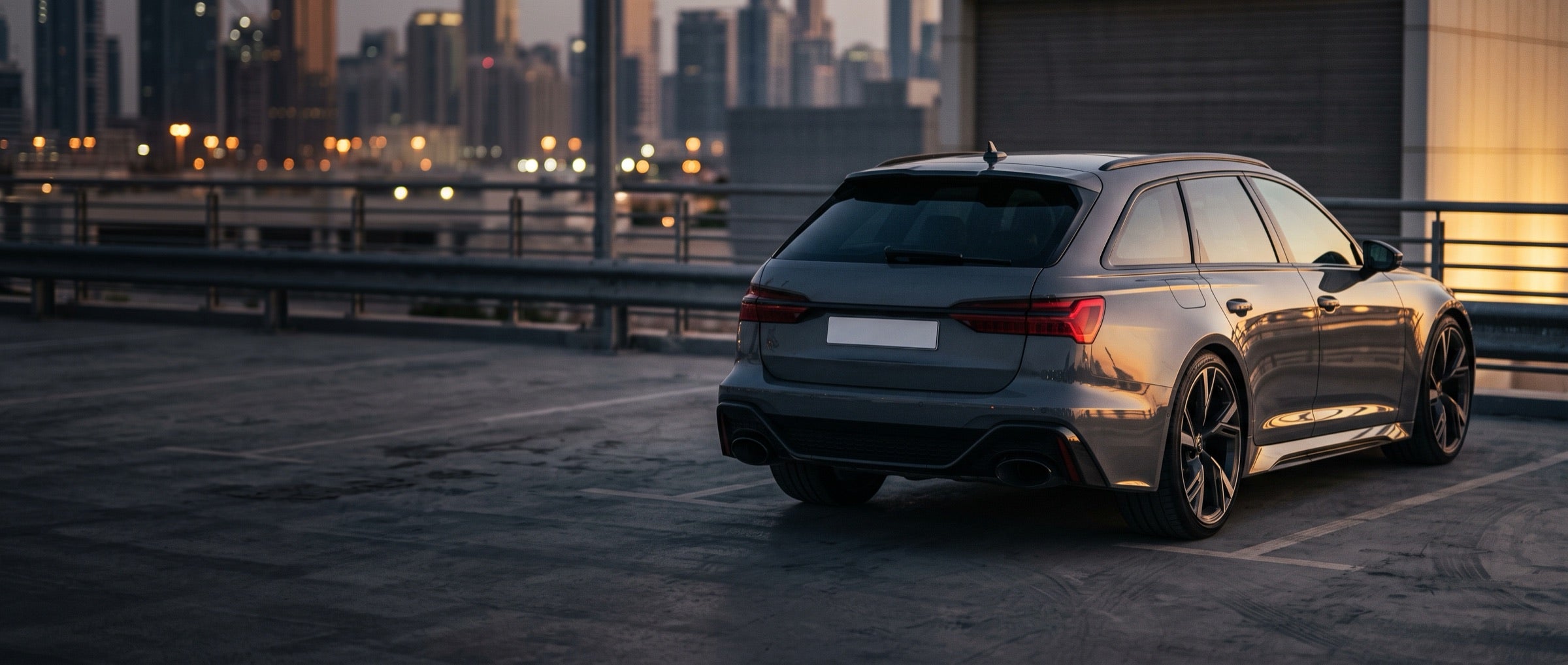 Grey estate car on a rooftop car park with a city skyline at dusk
