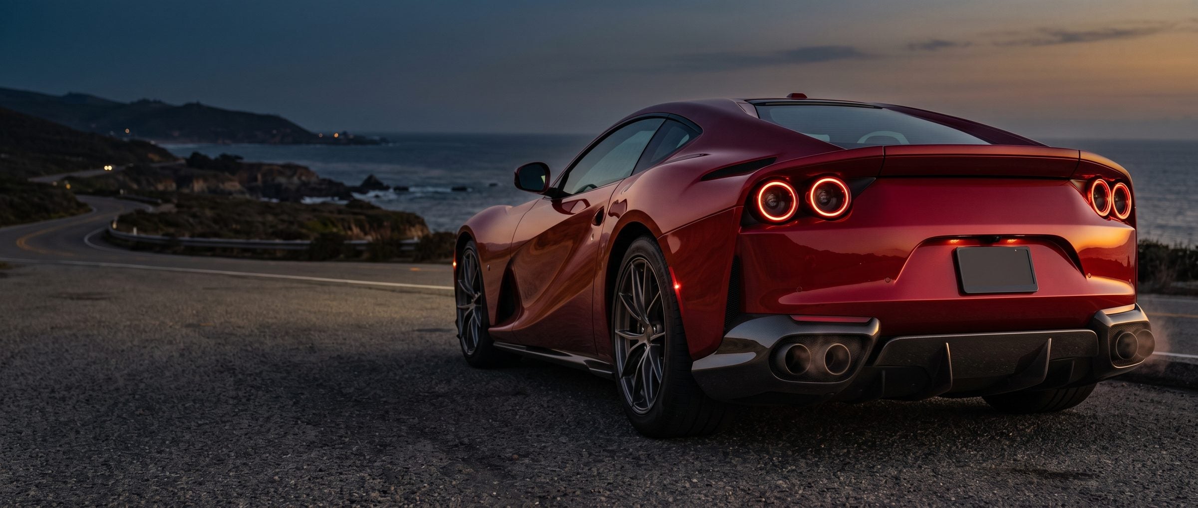 Red Italian supercar on a coastal road at dusk
