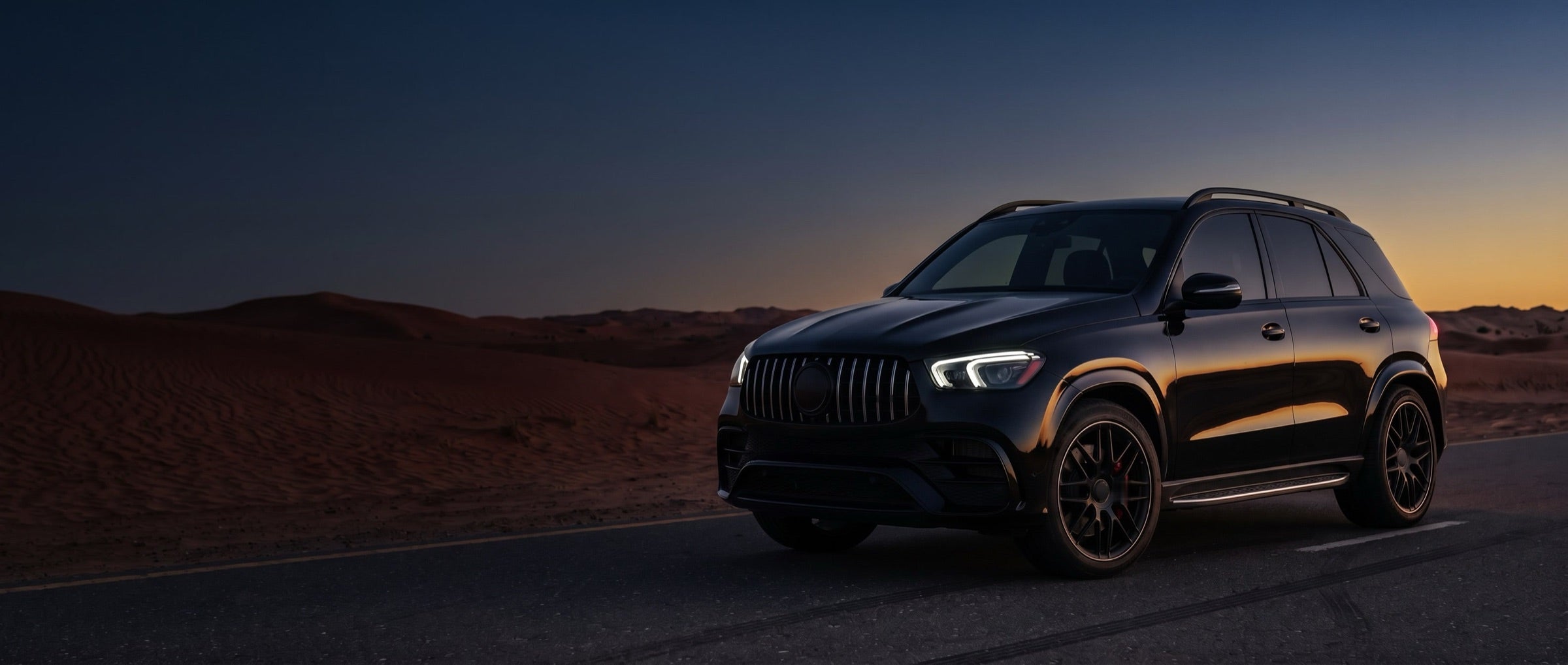 Black SUV on a desert road at dusk