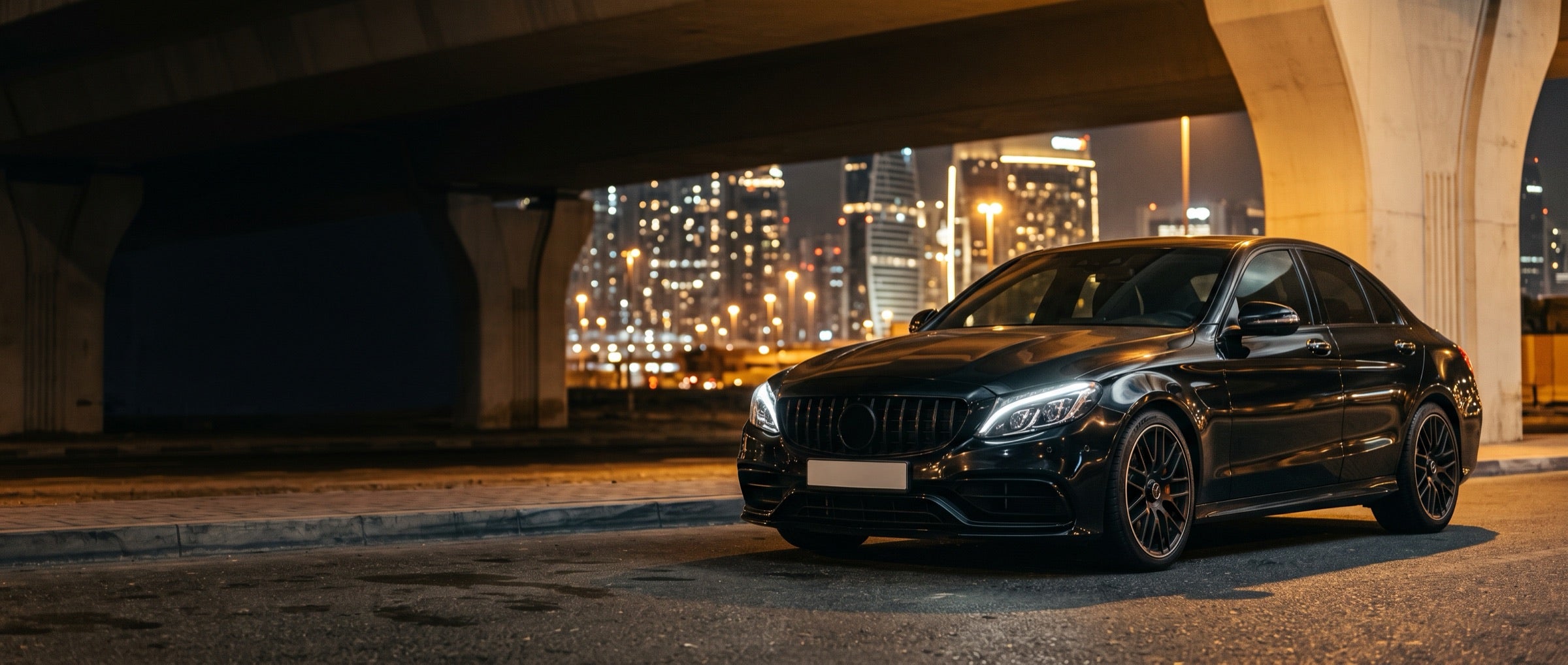 Black saloon under a bridge with a city skyline at night