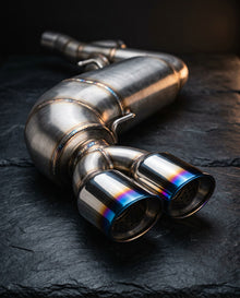 Stainless steel rear silencer with two oval titanium-blue tips on dark slate
