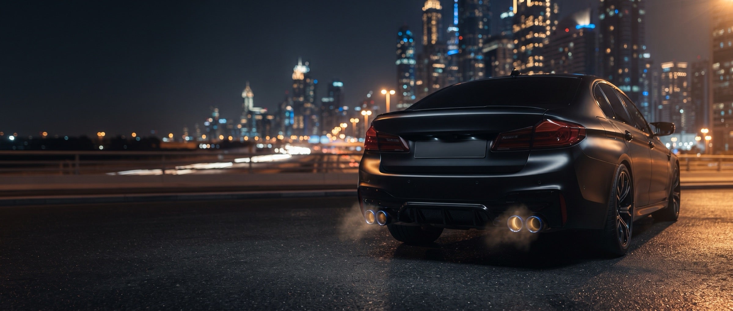 Rear of a black saloon with exhaust tips on a city road at night
