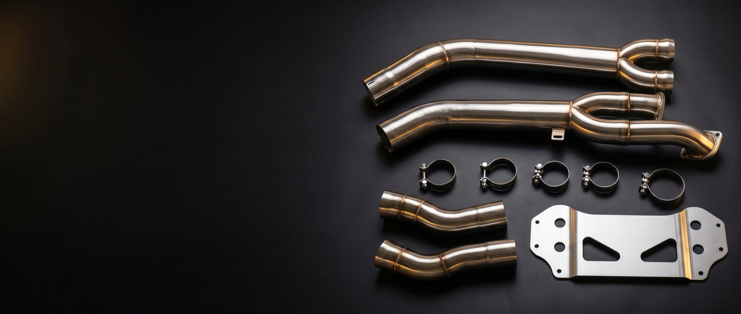 Midpipe kit with clamps and a mounting bracket laid out on black