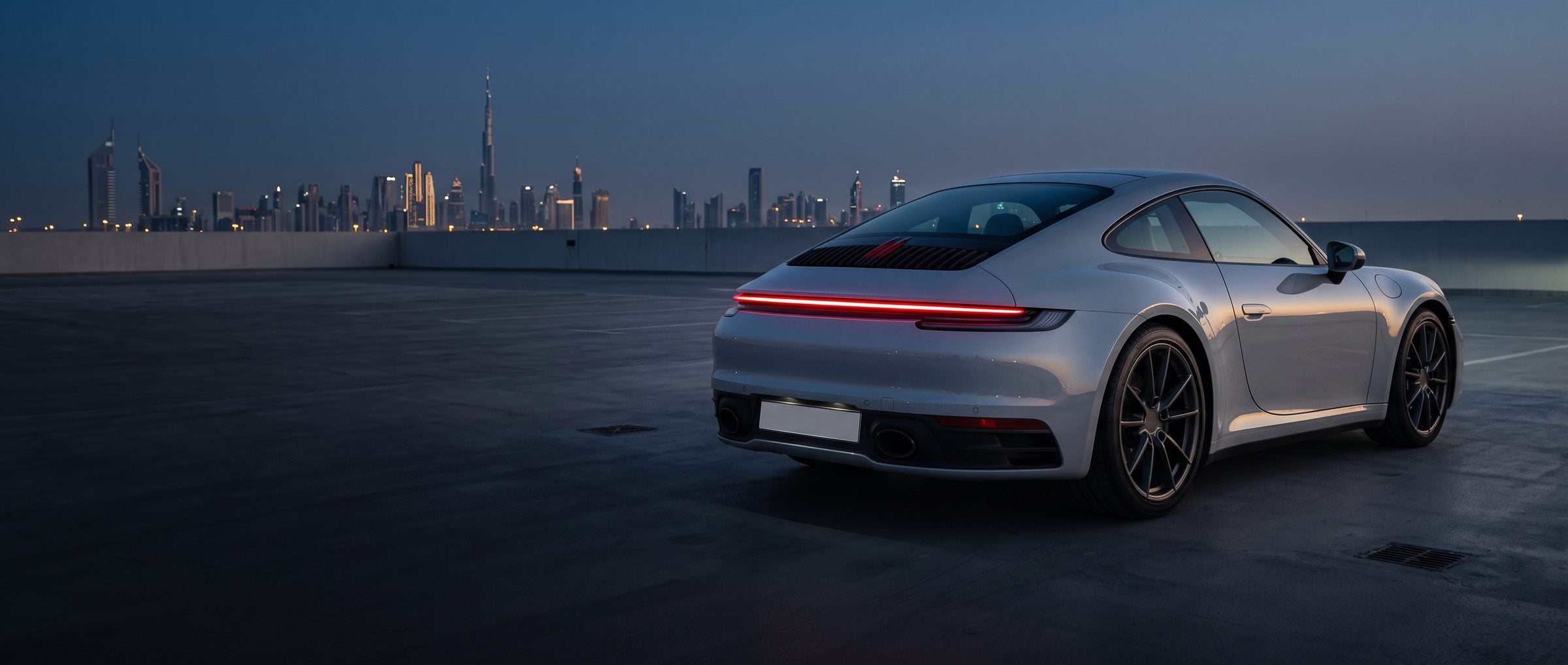 Grey sports coupe on a rooftop car park at blue hour