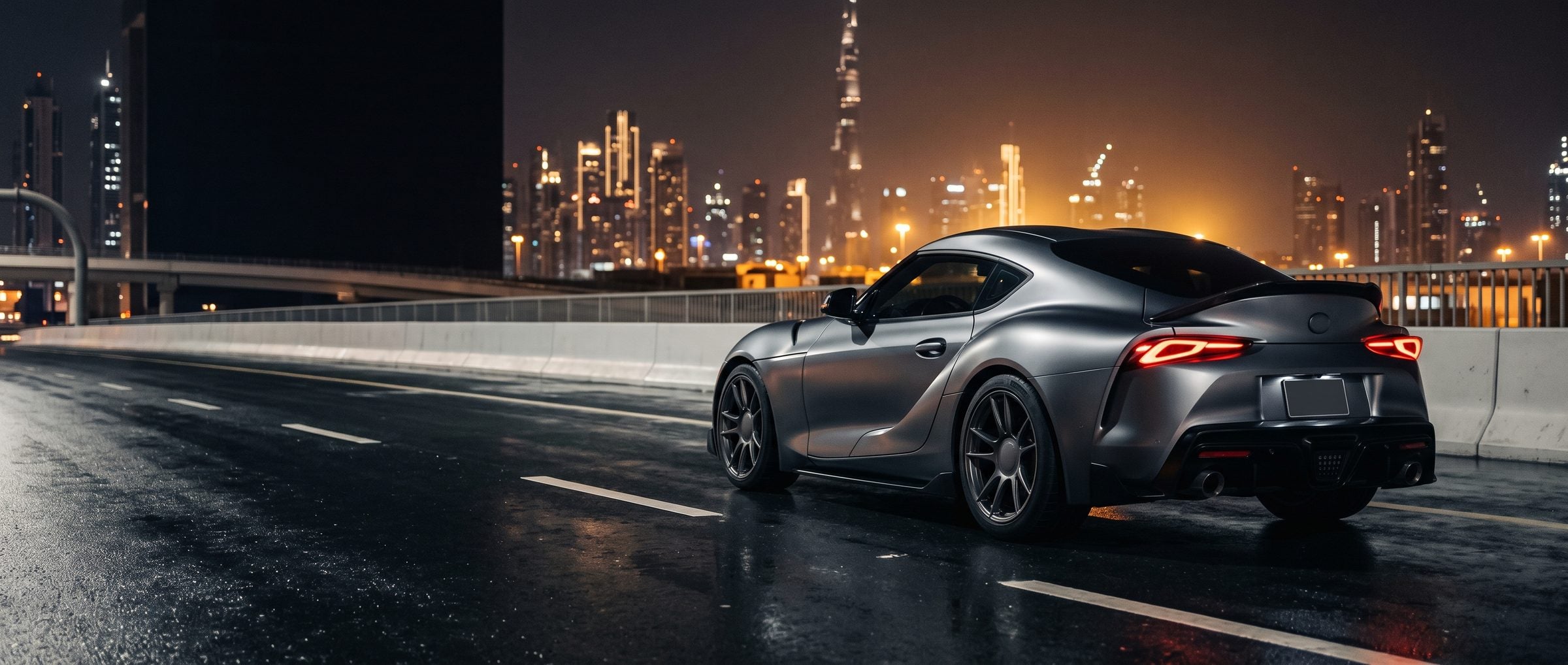 Grey sports coupe on a wet highway at night