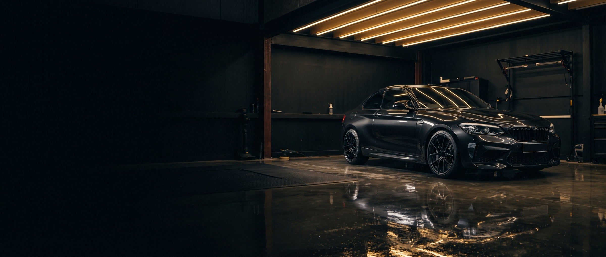 Black car in a dark garage under ceiling lights